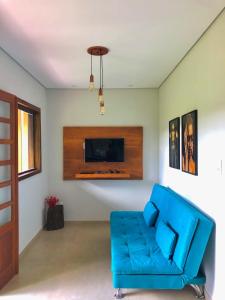 a living room with a blue couch and a tv at Vila Verde Chalés-Serro in Sêrro