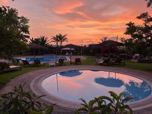 uma grande piscina com um pôr-do-sol ao fundo em Bungalows de Casa Verde em Mala
