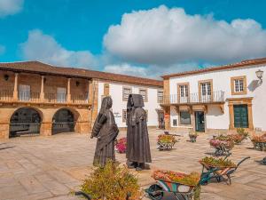 two statues of nuns standing in a courtyard at BUTEKO HOUSE AL in Miranda do Douro