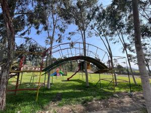 un parque infantil con tobogán en un parque con árboles en Bungalows de Casa Verde, en Mala