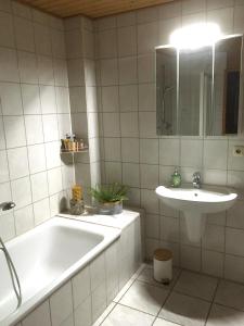 ein weißes Badezimmer mit einer Badewanne und einem Waschbecken in der Unterkunft Kranich-Holzferienhaus 'Kleine Auszeit' in Rehden