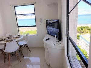 uma sala de estar com uma mesa e uma televisão e uma mesa e cadeiras em Apto de frente para o Mar, Piscina na cobertura em Recife
