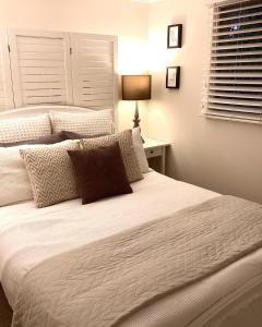 Jacaranda House Garden Suite في بريزبين: غرفة نوم بسريرين مع شراشف بيضاء