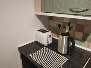 a kitchen counter with a toaster and a tea kettle at Ella's Place in Luton