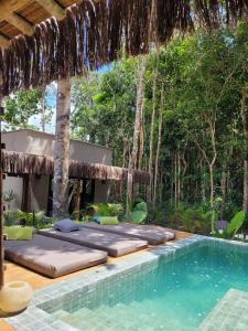 una piscina resort con camas y árboles en el fondo en CASA SUKHA Hotel, en Trancoso