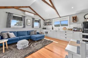 ein Wohnzimmer mit einem blauen Sofa und einer Küche in der Unterkunft Wakefields - an enchanting mountain view cottage in Mole Creek