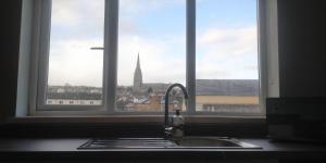fregadero de cocina y ventana con vistas a una iglesia en Free Derry Apartments, en Derry Londonderry