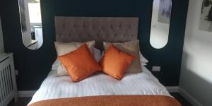 Una cama con dos almohadas naranjas encima. en Free Derry Apartments en Derry