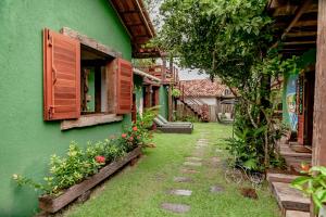 un edificio verde con ventanas y flores en el patio en Canto dos Sonhos Caraíva, en Caraíva