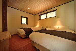 een slaapkamer met 2 bedden en 2 ramen bij Syoubun in Minakami
