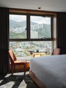 釜山にあるHotel tt Gupoのベッドと大きな窓が備わるホテルルームです。