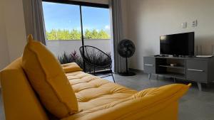 Casa em Garopaba في غاروبابا: غرفة معيشة بها أريكة صفراء وتلفزيون