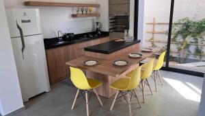 Casa em Garopaba في غاروبابا: مطبخ بطاولة خشبية وكراسي صفراء