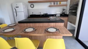 Casa em Garopaba في غاروبابا: مطبخ بطاولة خشبية وكراسي صفراء