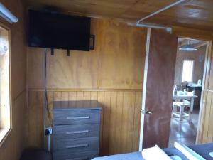a bedroom with a tv on the wall and a dresser at Cabañas La Frontera. in Puerto Natales