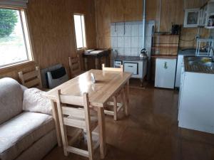 a living room with a wooden table and a kitchen at Cabañas La Frontera. in Puerto Natales