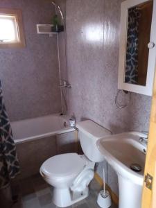 a bathroom with a toilet and a sink and a tub at Cabañas La Frontera. in Puerto Natales