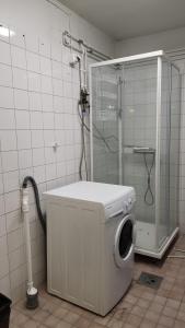 uma máquina de lavar roupa na casa de banho com um chuveiro em Ingala em Inkoo