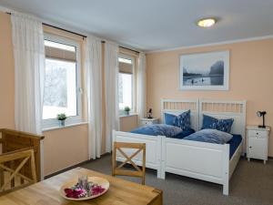 a bedroom with a bed and two windows and a table at Ferienwohnung im Sauerland in Erndtebrück