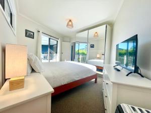 een slaapkamer met een bed, een bureau en ramen bij Blue Lily Bungalow in Katoomba