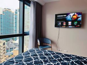 a bedroom with a bed and a flat screen tv at Eastwood High Life - Spectacular City View in Manila