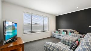 a living room with two couches and a flat screen tv at Ocean Bridge Lakes Entrance in Lakes Entrance