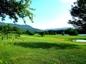 a field with a lake and mountains in the background at Williams Island Room at Tennessee RiverPlace in Chattanooga