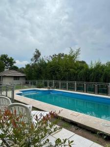 una piscina en un patio con 2 sillas en Descanso en Villa Allende, familia, golf, amigos en Villa Allende
