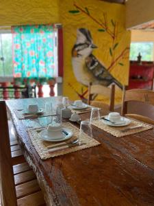 una mesa con platos y tazas y un pájaro pintado en la pared en Pousada Encontro de Rios, en Lençóis