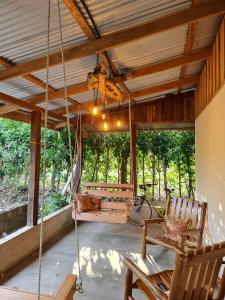um alpendre com duas cadeiras e um baloiço em Casa Briza em Península de Nicoya