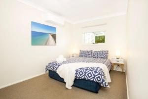 a white bedroom with a bed and a window at Hayes Beach House I Award Winner I 4 Mins to Beach in Callala Beach