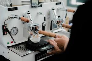 a person is making a cup of coffee in a machine at CERIA HOTEL at Alun Alun Yogyakarta in Yogyakarta