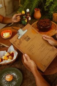 una persona leyendo un libro en una mesa con una cruz en Casa da Esquina Caraíva, en Caraíva