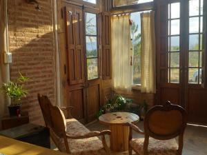 Habitación con 2 sillas, mesa y ventanas en Arrullo del viento en Villa Yacanto