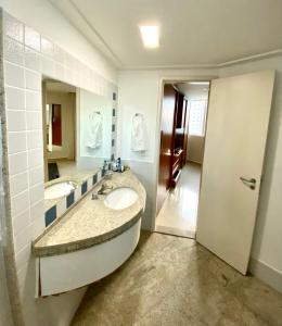 a bathroom with two sinks and a large mirror at Fabulosa Suite 903 em Flat Alto Padrão in Londrina