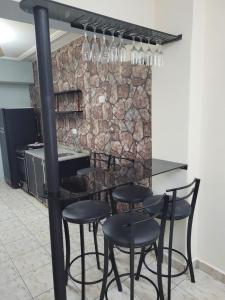 un bar con sillas negras y una pared de piedra en Departamento Calle Corrientes en San Miguel de Tucumán