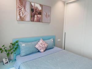 um quarto com uma cama azul com almofadas em ALTARA Residences Quy Nhơn-Sam n' Sea Apartment-Căn hộ homestay view biển có hồ bơi em Quy Nhon