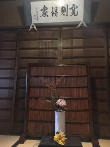 une table avec un vase de fleurs et un signe dans l'établissement Azukiya, à Kyoto