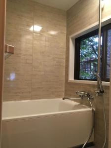 a bath tub in a bathroom with a window at Azukiya in Kyoto