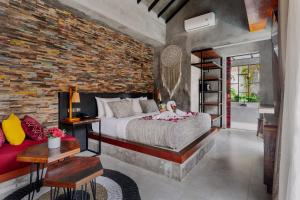 a bedroom with a bed and a brick wall at Vinna Villa Seminyak in Kerobokan