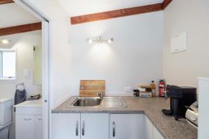 a kitchen with a sink and white cabinets at Rowling Road Studio in Kaiteriteri