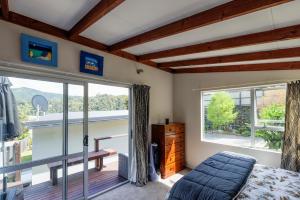 a bedroom with a bed and a large window at Rowling Road Studio in Kaiteriteri
