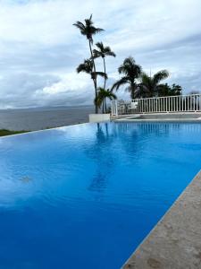 a large blue swimming pool with the ocean in the background at Amazing views!! in Santa Bárbara de Samaná