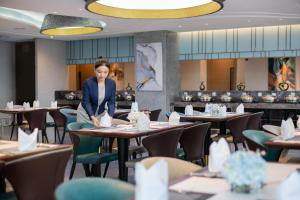 a woman standing at a table in a restaurant at Xin'an Yihao Hotel - Near Xiamen Railway Station, near Vientiane City, minibar is free in Xiamen