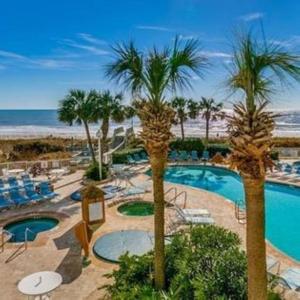 un complejo con piscina, palmeras y playa en Sea Watch Resort en Myrtle Beach