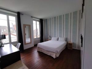 sypialnia z białym łóżkiem i 2 oknami w obiekcie Smart Inn Melun Centre- Appartement 2 chambres w mieście Melun