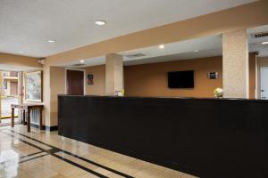a hotel lobby with a large black counter and a tv at Days Inn by Wyndham Dallas Irving in Irving