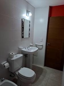 a white bathroom with a toilet and a sink at MODERNO DUPLEX Con COCHERA in Luzuriaga