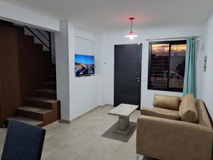 a living room with a couch and a staircase at MODERNO DUPLEX Con COCHERA in Luzuriaga