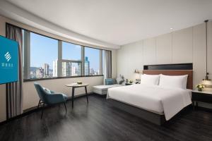 a hotel room with a bed and a table and a chair at Xin'an Yihao Hotel - Near Xiamen Railway Station, near Vientiane City, minibar is free in Xiamen